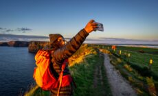 Une voyageuse prenant un selfie face aux Falaises de Moher -  Tolo