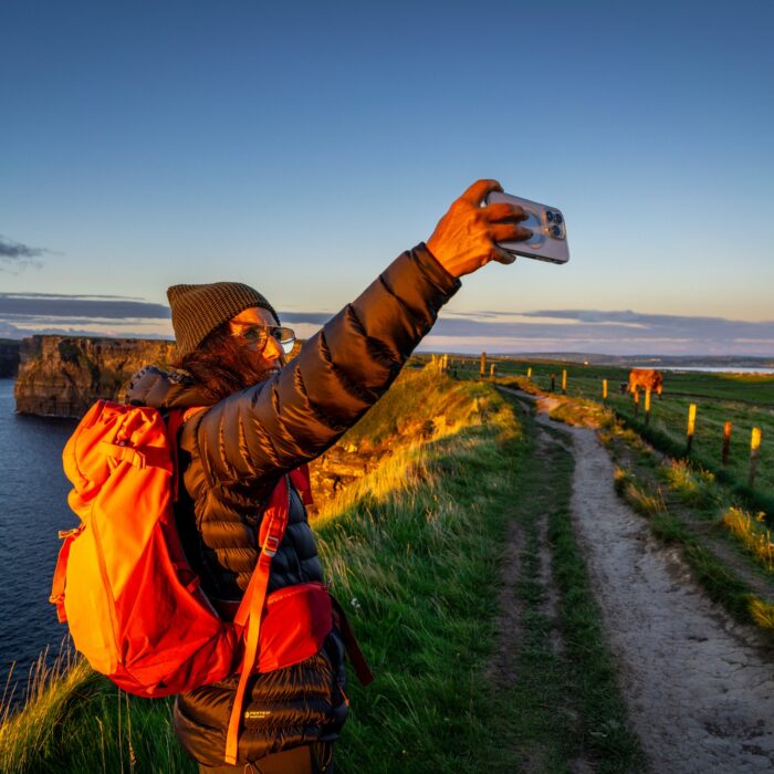 Une voyageuse prenant un selfie face aux Falaises de Moher -  Tolo