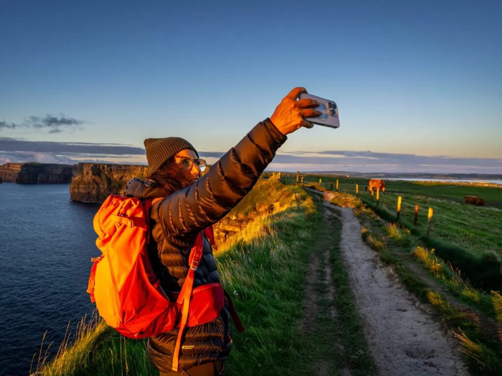 Une voyageuse prenant un selfie face aux Falaises de Moher -  Tolo