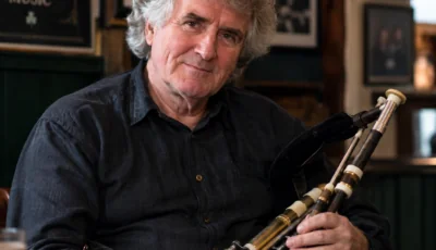 Paddy Keenan tenant ses uilleann pipes dans un pub irlandais